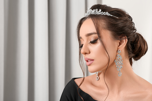 Beautiful young woman wearing luxurious tiara indoors, space for text