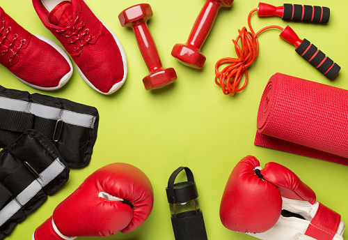 Red sport equipment on color background, top view