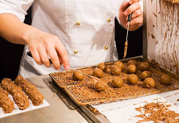 Chocolatier working Chocolatier making truffels. Motion blur. chocolate truffle making stock pictures, royalty-free photos & images