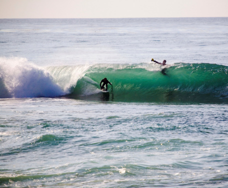 Surf photographer aims his camera at a surfer ducking into a nice tube.