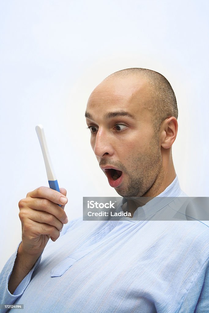 Pregnant again? young man with funny face looking surprised at the pregnancy test Men Stock Photo