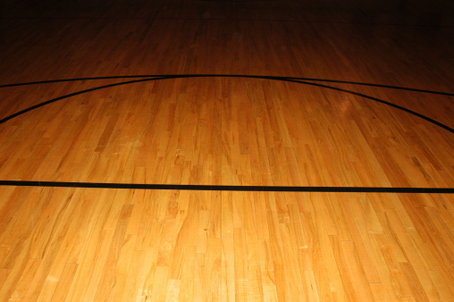 Wooden basketball floor showing three point line and foul line.