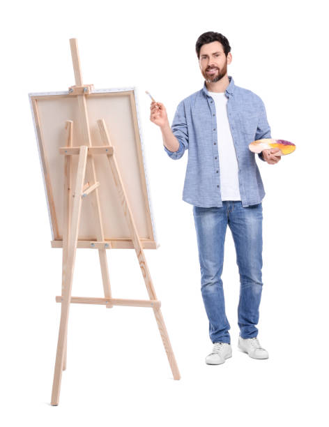 istock Happy man painting with brush against white background. Using easel to hold canvas 1721254444