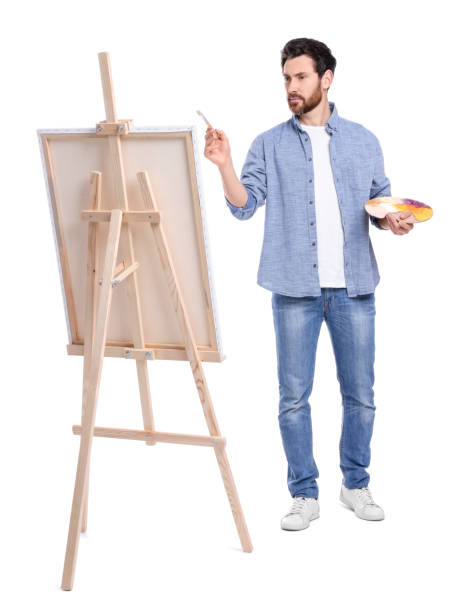istock Man painting against white background. Using easel to hold canvas 1721254965