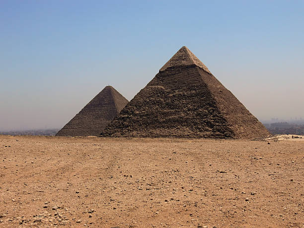 Silhouette of the Great Pyramids of Giza at sunset with a dramatic sky in the background