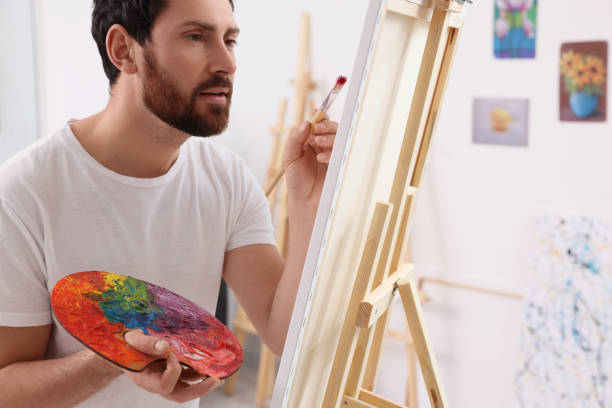istock Man painting in studio. Using easel to hold canvas 1721256038
