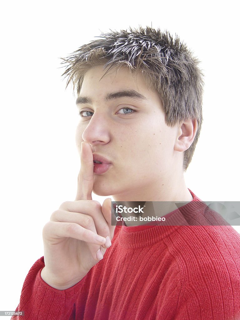 teen - the secret young man in red sweater holding his finger to his lip like he has a secret Adult Stock Photo