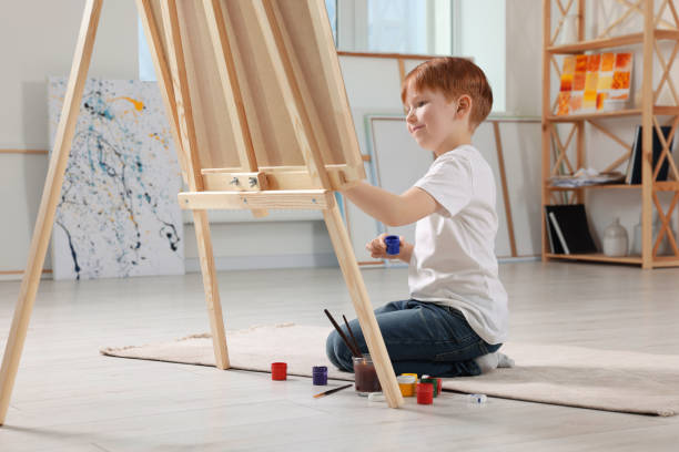 istock Little boy painting in studio. Using easel to hold canvas 1721257117