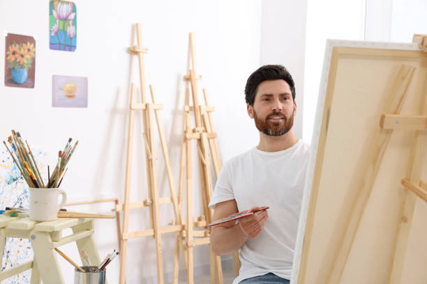 istock Man painting in studio. Using easel to hold canvas 1721258222