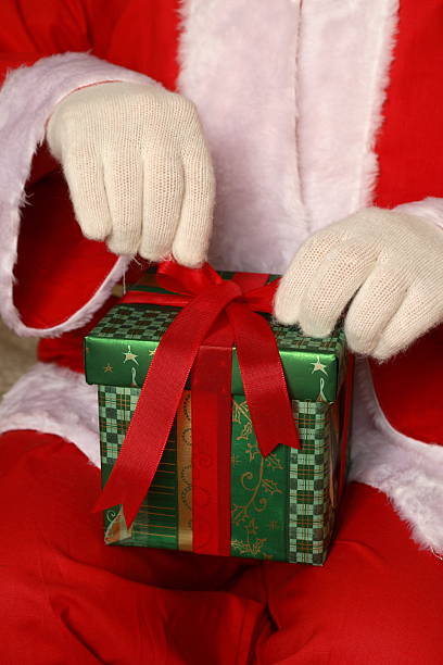 istock Santa Putting Bow Onto Box (vertical) 172125866