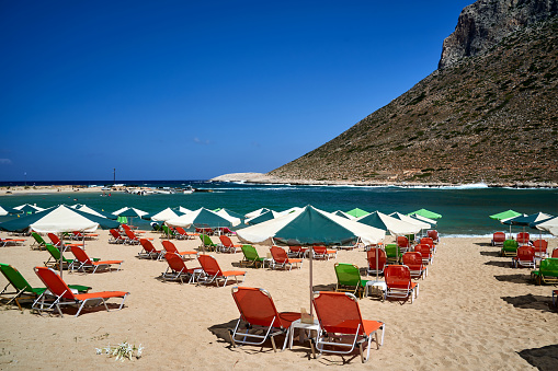 Cefalu, Italy - September 19, 2014: People enjoying the sun at a crowded beach near the old town of Cefalu, Sicily.
