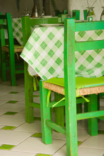 Subject: Vertical close-up of table settings in a casual Mexican restaurant, featuring checkered lime green tablecloths and floors, and coordinating lime green chairs.