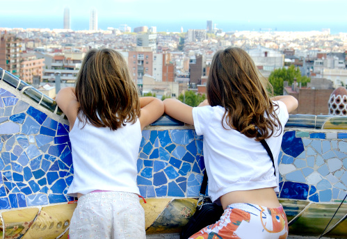 Two young girls looking to Barcelona from a bench from Antonio Gaudi's Parc Guell.