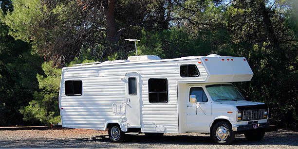 Motorhome parked along road Motorhome RV parked along road. Vehicle is all white, writing and color along the vehicle's side is gone RV truck stock pictures, royalty-free photos & images