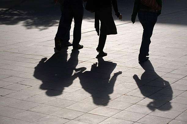 istock sun casting shadows over young people walking in a street 172129147