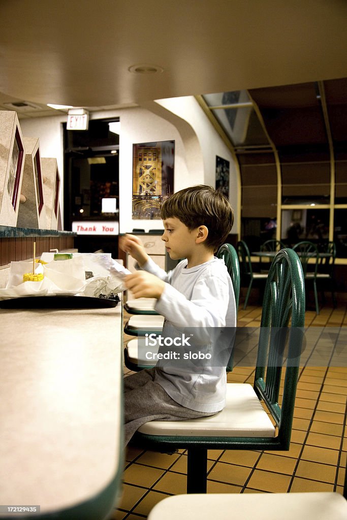 Giovane ragazzo avendo una nottata spensierata mangiare Fast Food - Foto stock royalty-free di Bambino