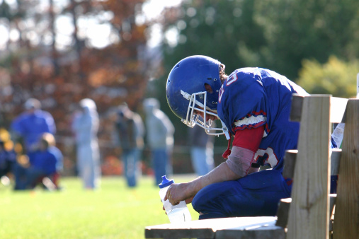 Football player sits on the bench exhausted