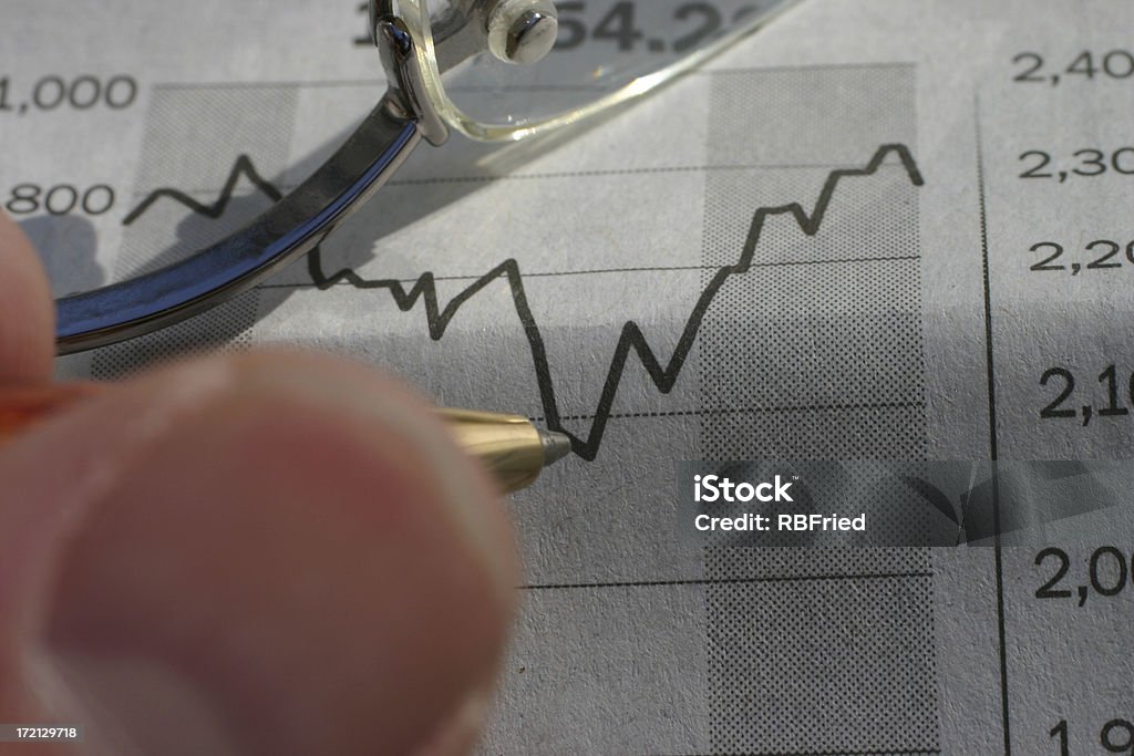 Investing a man charting investments in a newspaper Analyzing Stock Photo