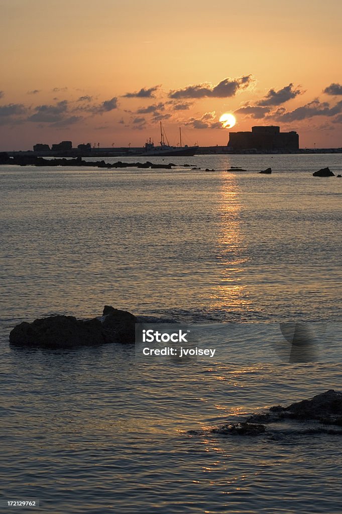 Paphos harbour at sunset A view of Paphos harbour (& castle) at sunset - rock in foreground. Paphos Stock Photo