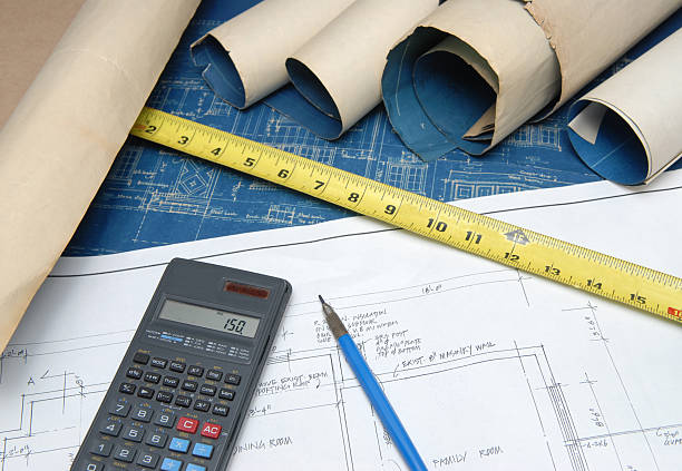 Calculator with blueprints for estimates of renovation costs stock photo