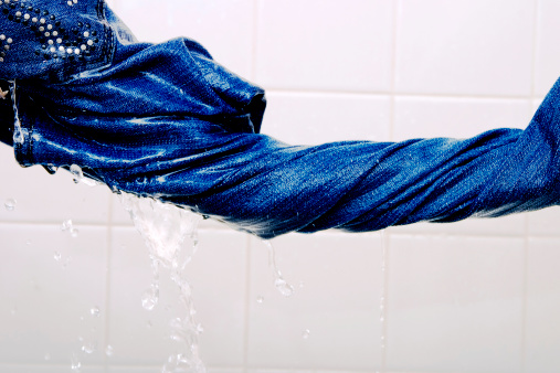 Squeezing washed jeans to get ready of excess water.