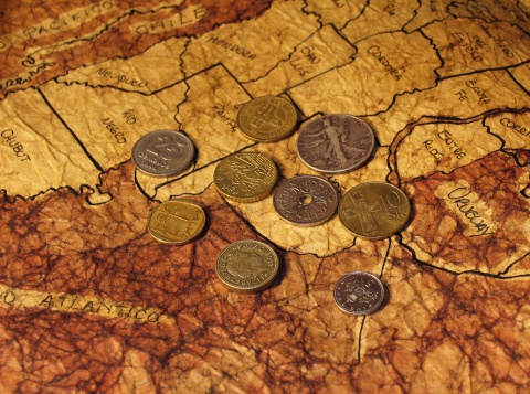 Various coins from different countries laid on a map of Argentina