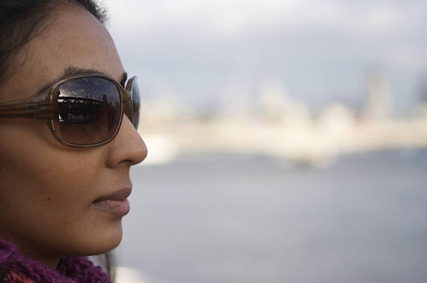 Modern British Asian girl in profile, looking right, Blackfriar's Bridge (out of focus) in the background.