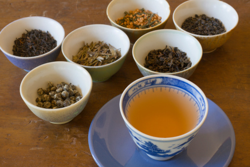 Half empty cup of tea on a wooden table, no handle on the cup, interior is yellow. Horizontal indoors shot with copy space. No people.