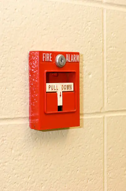 Photo of A bright red fire alarm on a concrete wall