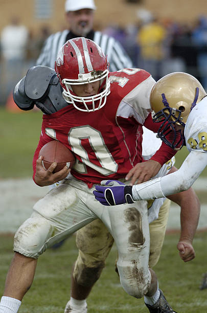Determined American football player making a touchdown while passing through defensive players on playing field. Black and white photography.