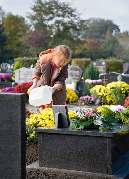 istock Young girl at the graveyard, watering flowers 172132185