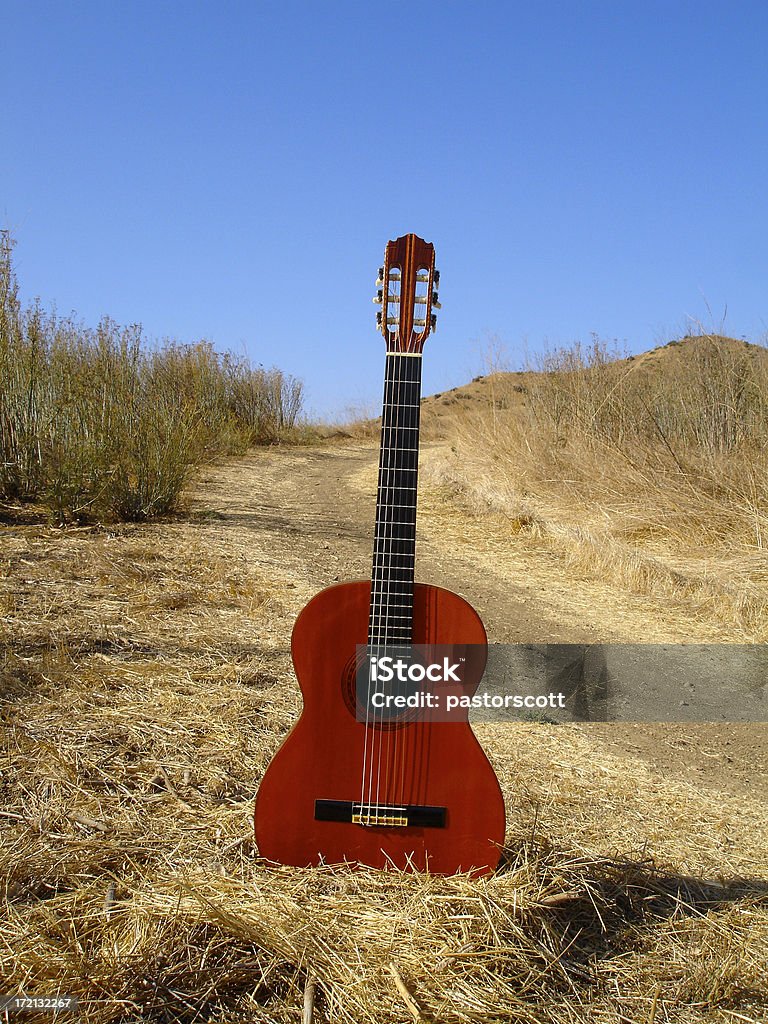 Guitar Series                                Guitar on dirt path surrounded by dried grass with clear sky Absence Stock Photo