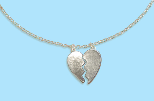 A silver broken heart pendant on a blue background