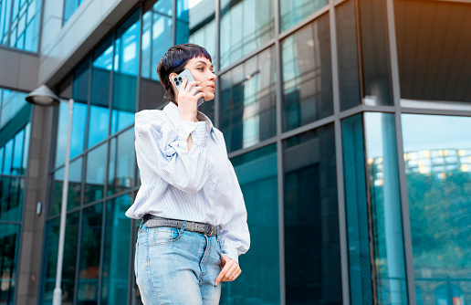 a woman in a blue shirt uses a mobile phone and a business center in the background