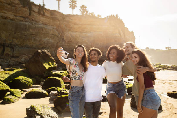 istock Glad young multiethnic people with smartphone make selfie, have fun together on ocean beach 1721335931