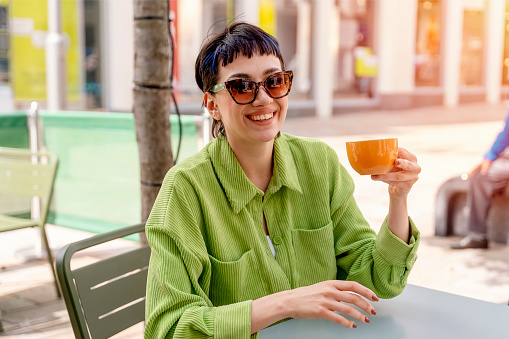 woman having coffee at the street cafe with friend outside, having fun time. lifestyle concept
