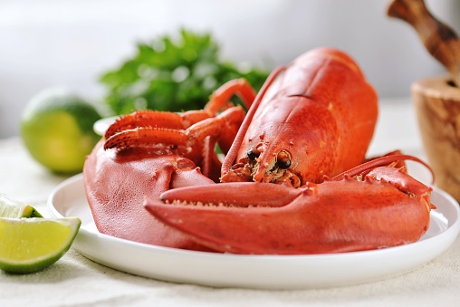 whole boiled lobster on a white plate with lime slices