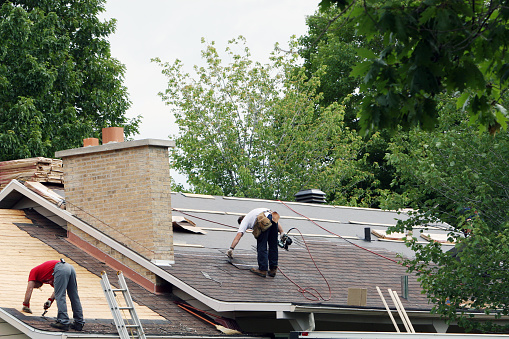 Close-up on damaged asphalt shingles over the roof of a shed in the backyard