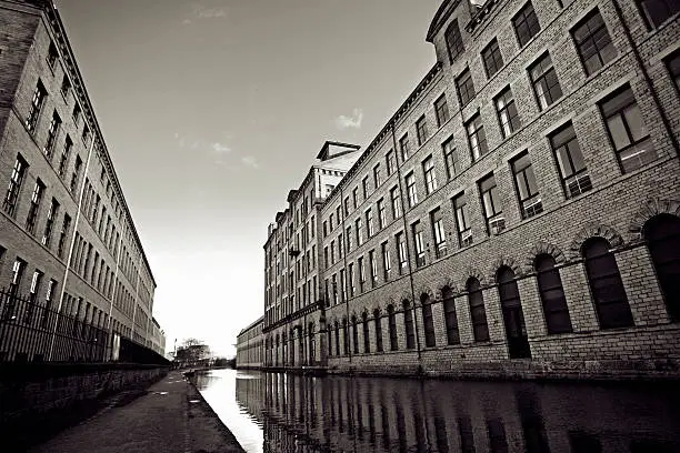 "Sepia image of the old victorian textile mills and canal in Saltaire, Yorkshire, England.  Built by Sir Titus Salt at the time it was the largest industrial building in the world. Now offices, apartments and an art gallery."