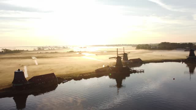 Ancient wooden windmills of Zaanse Schans during sunrise. The golden rays reveal the history of the Netherlands. 4k video