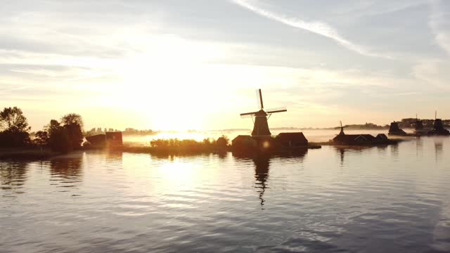 Ancient wooden windmills of Zaanse Schans during sunrise. The golden rays reveal the history of the Netherlands. 4k video