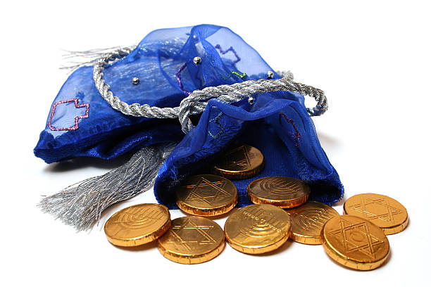 A full view of a colorful Hannukah-themed bag spilling out gold gelt pieces.