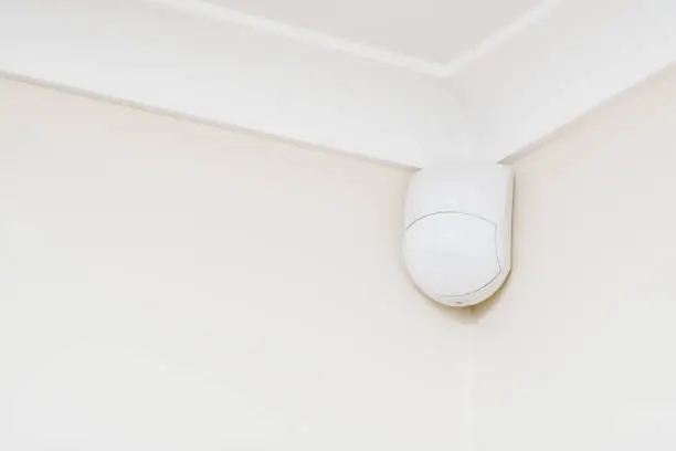 Security alarm sensor in corner of room.