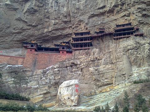 Datong, Shanxi, China- March 2, 2013:  the Hanging Temple Mt. Heng, located 60 kilometers southeast of Datong, China, in the Shanxi province, is one of the world’s forgotten wonders. Clinging to a crag of Hengshan mountain, in apparent defiance of gravity, it consists of 40 rooms linked by a dizzying maze of passageways. The temple is said to have been built during 386-534. It was constructed by drilling holes into the cliffside into which the poles that hold up the temples are set. Here is external view of the temple.