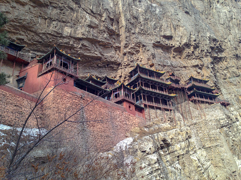 Datong, Shanxi, China- March 2, 2013:  the Hanging Temple Mt. Heng, located 60 kilometers southeast of Datong, China, in the Shanxi province, is one of the world’s forgotten wonders. Clinging to a crag of Hengshan mountain, in apparent defiance of gravity, it consists of 40 rooms linked by a dizzying maze of passageways. The temple is said to have been built during 386-534. It was constructed by drilling holes into the cliffside into which the poles that hold up the temples are set. Here is external view of the temple.