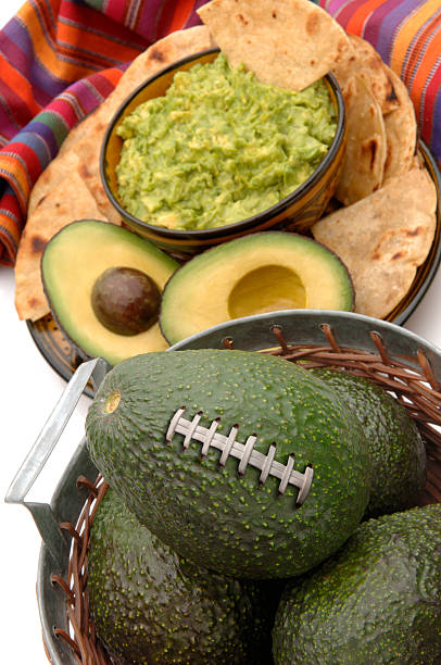 Ingredients for avocado dip flying and falling in stone bowl lemon, coriander, chili, garlic, tomato, sliced nachos in Mexico