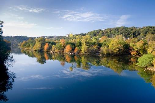 trees and colorful leaves reflecing on water under blue sky