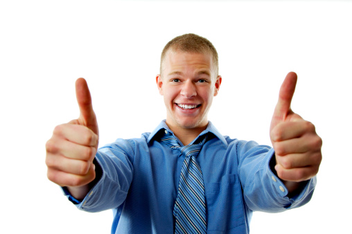 Confident young handsome man in shirt and tie showing his thumbs up and smiling while standing against white background