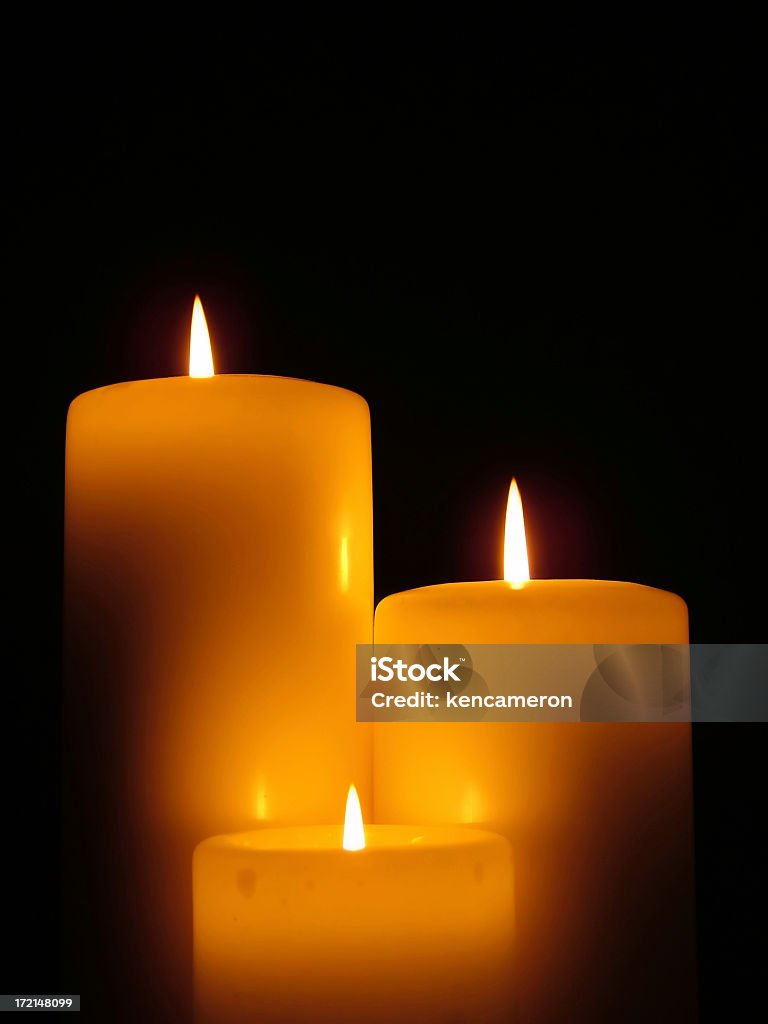 Three different size lit candles against a black background "Group of three candles, lit by each other." Architectural Column Stock Photo