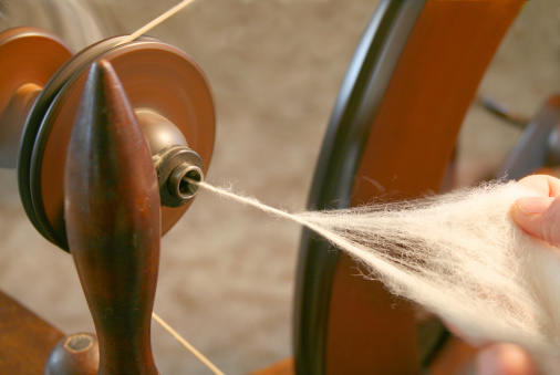 Spinning focus on wool in hand. Motion blur on spinning wheel.